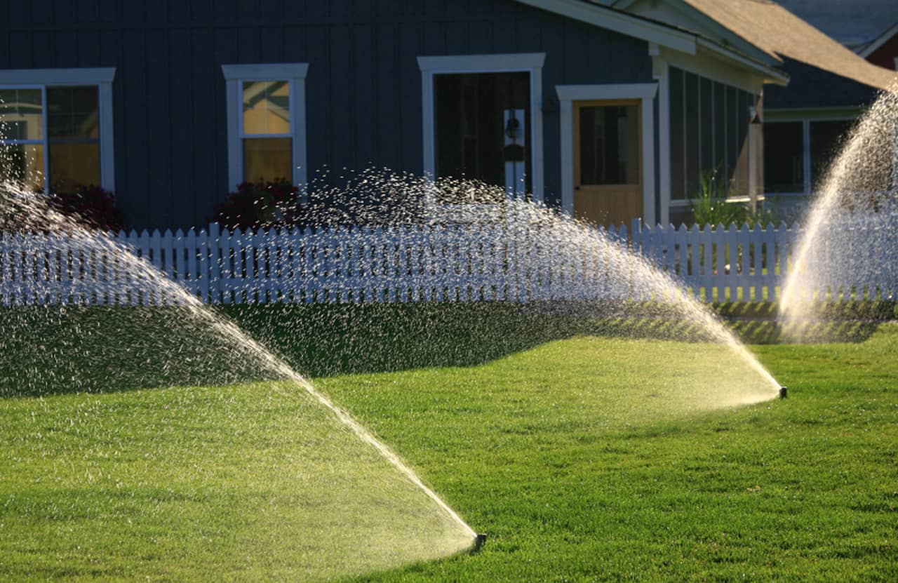 Sprinkler system spraying water on a lush green lawn