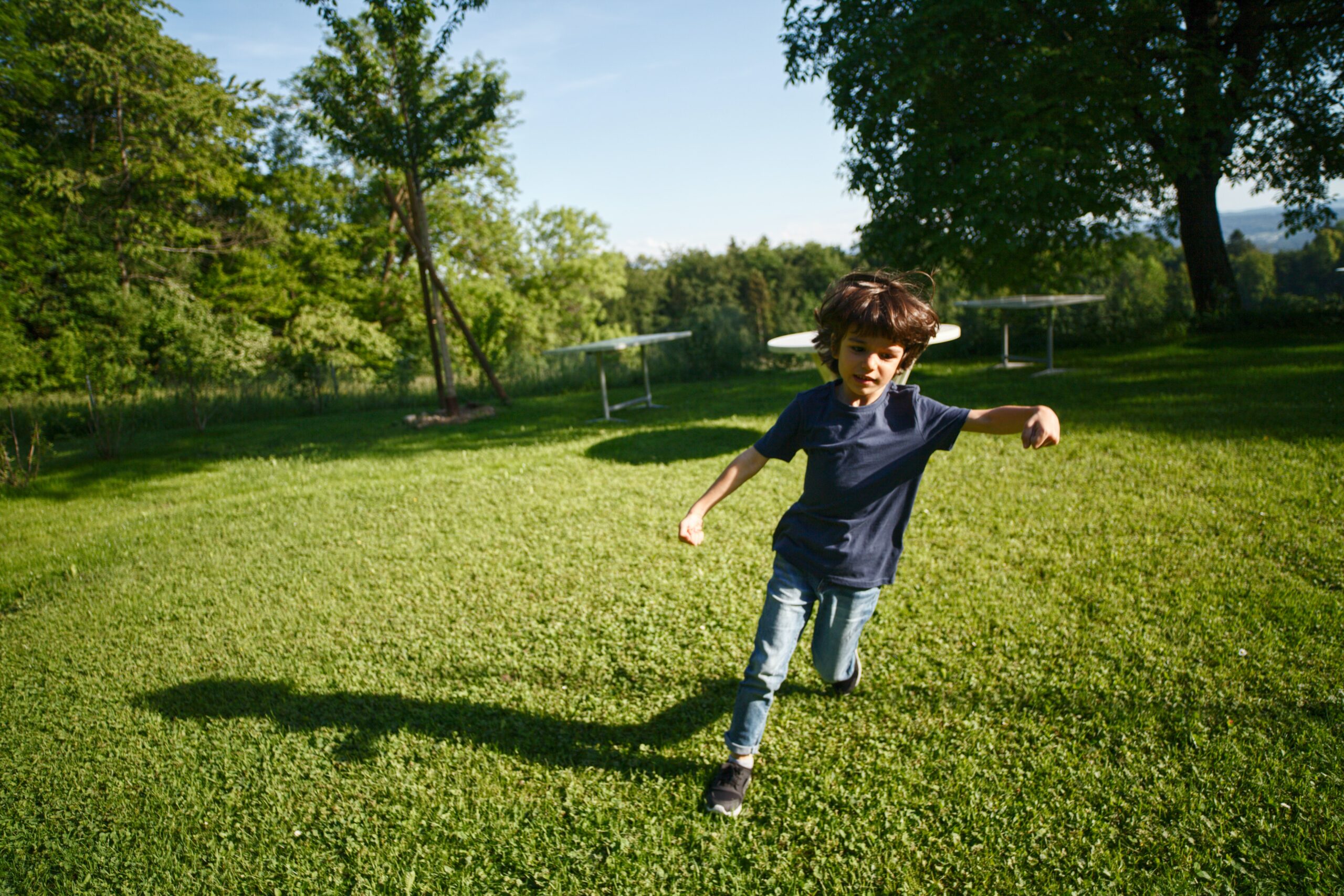 Young boy running on a pristine lawn kept up by lawn aeration services